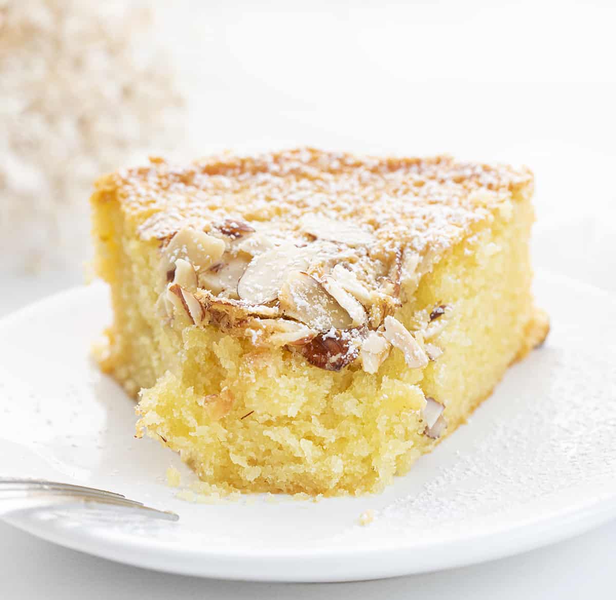 Slice of Almond Cake on a White Plate with a Bite Removed and Fork Resting on its Side. Almond Cake, French Almond Cake, Moist Almond Cake, How to Make Almond Cake, Almond Cake Recipes, Easy Almond Cake Recipes, Baking, Dessert, Holiday Baking, Christmas Cake, Thanksgiving Cake, i am baker, iambaker