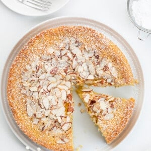 Almond Cake on a White Surface with Plates and Confectioners Sugar and a Slice Removed. Almond Cake, French Almond Cake, Moist Almond Cake, How to Make Almond Cake, Almond Cake Recipes, Easy Almond Cake Recipes, Baking, Dessert, Holiday Baking, Christmas Cake, Thanksgiving Cake, i am baker, iambaker