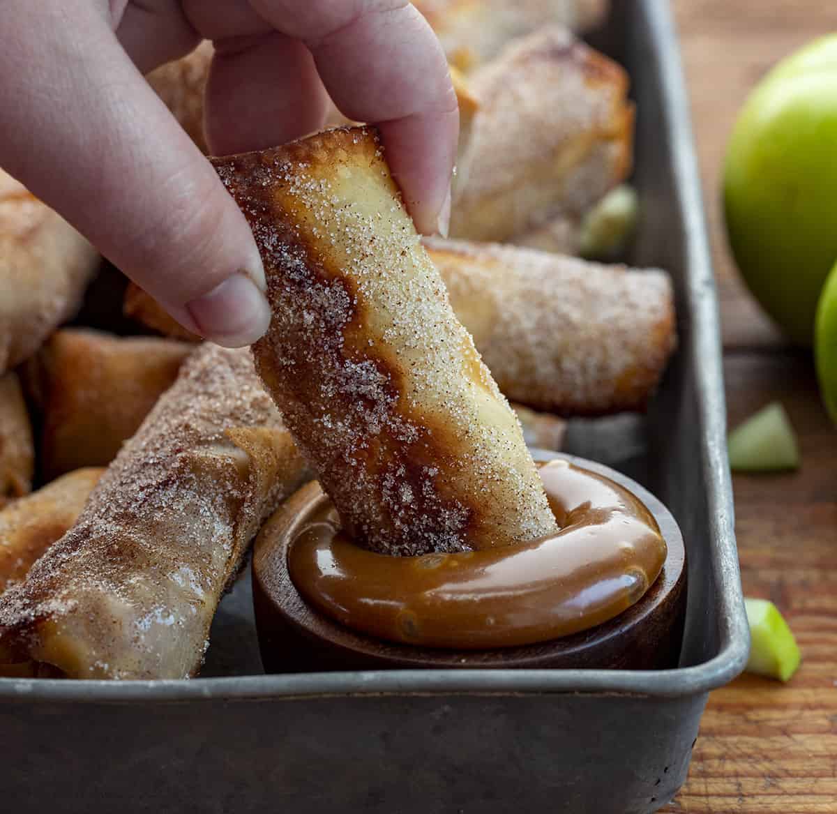 Hand Dipping Apple Pie Egg Rolls into Caramel Sauce. Dessert Egg Rolls, Apple Egg Rolls, Apple Pie Egg Rolls, Easy Apple Pie Recipes, Dessert, Air Fryer Apple Pie Egg Rolls, Oven Apple Pie Egg Rolls, Super Bowl Desserts, Thanksgiving Desserts, Christmas Desserts, Snacks, i am baker, iambaker