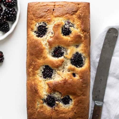 Blackberry Loaf on a White Counter with Blackberries and Knife on a White Towel.