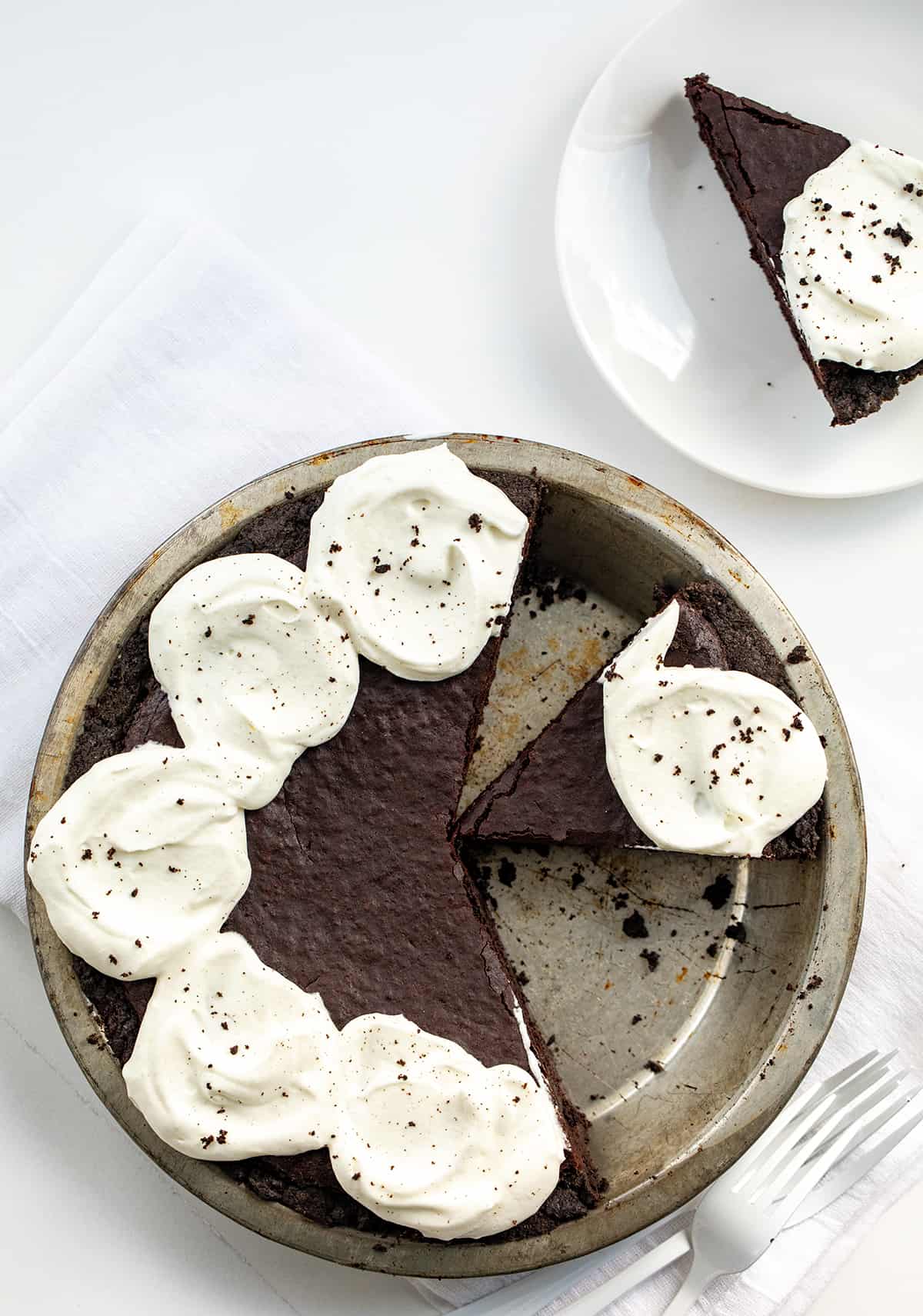 Pie Pan with Brownie Pie in it and a Few Pieces Removed on a White Counter.