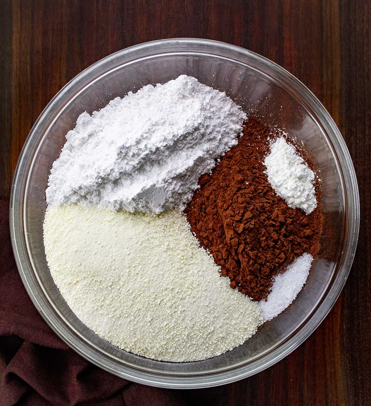 Ingredients for making homemade hot cocoa mix in a bowl on a cutting board.