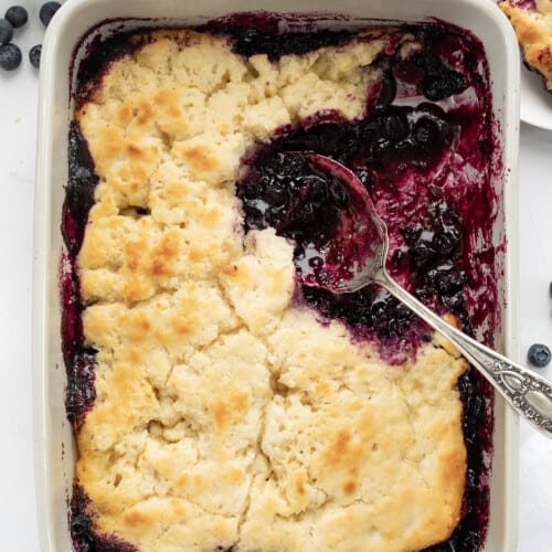 Looking Down on Butter Swim Biscuit Blueberry Cobbler with a Spoon in it and Some Removed.