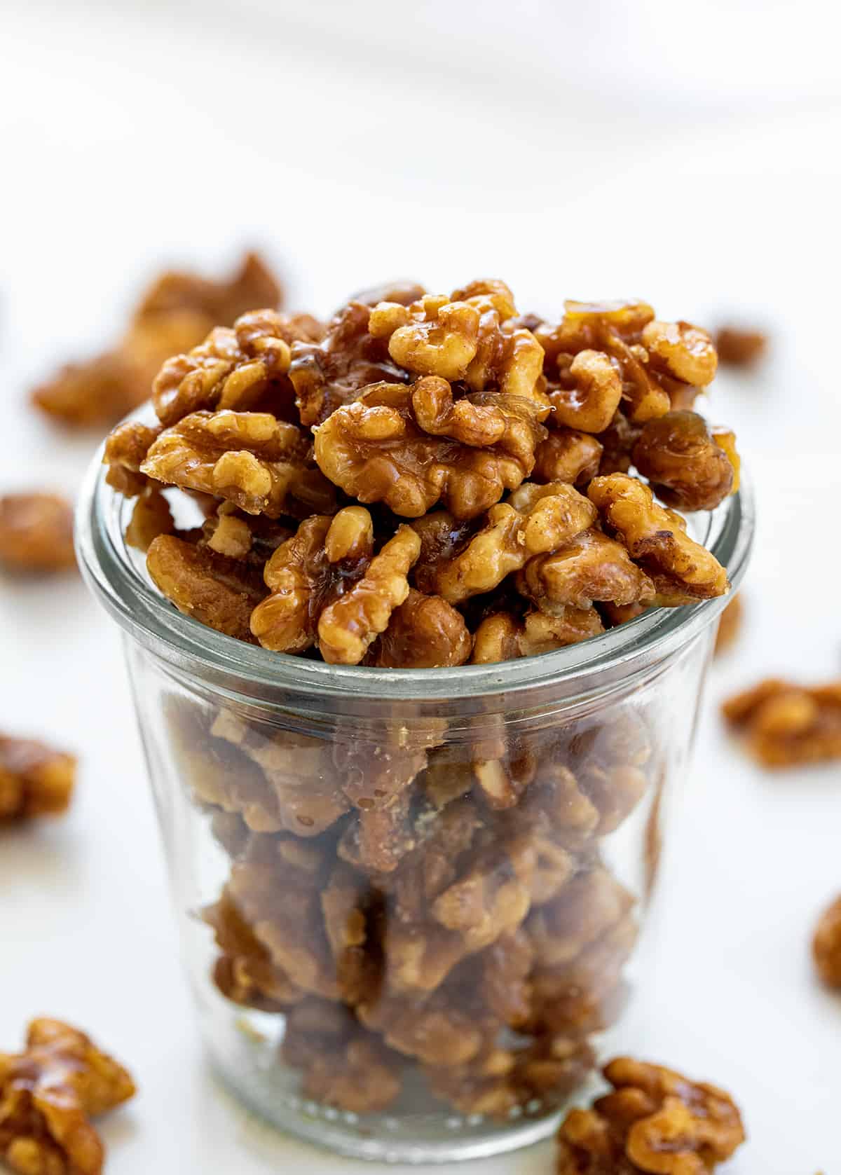 Jar of Candied Walnuts with Some Scattered Around it.
