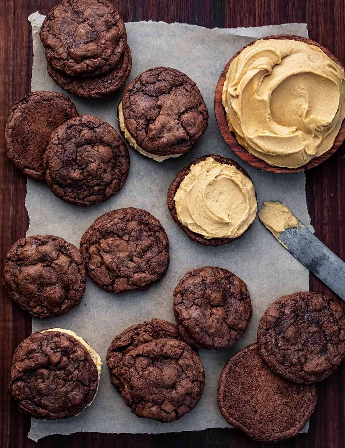 Cookies on a Dark Cutting Board with Peanut Butter Frosting and Adding Peanut Butter Frosting to Some Cookies.