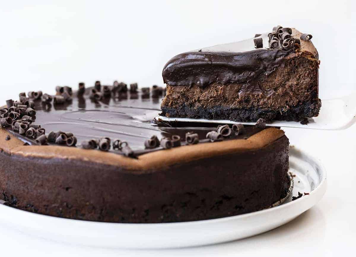 One Slice of Chocolate Cheesecake Being Removed from the Pan with White Spatula