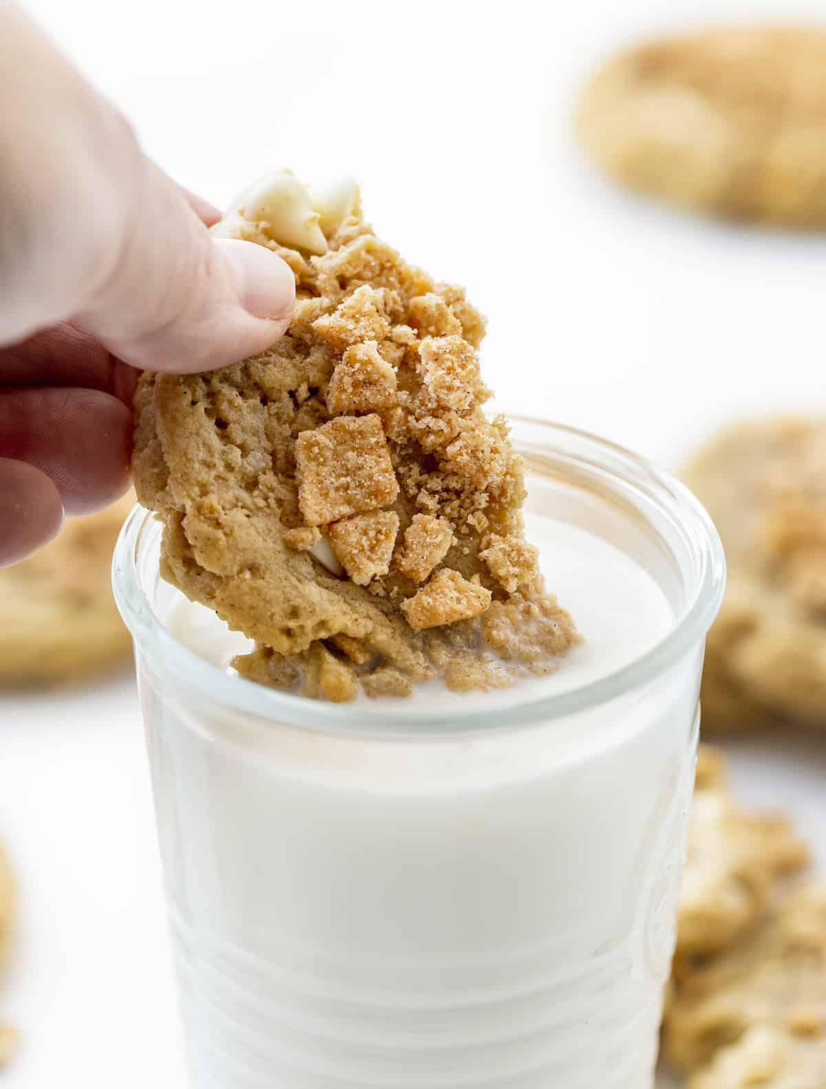 Hand Dipping a Cinnamon Toast Crunch Cookie Into Milk.