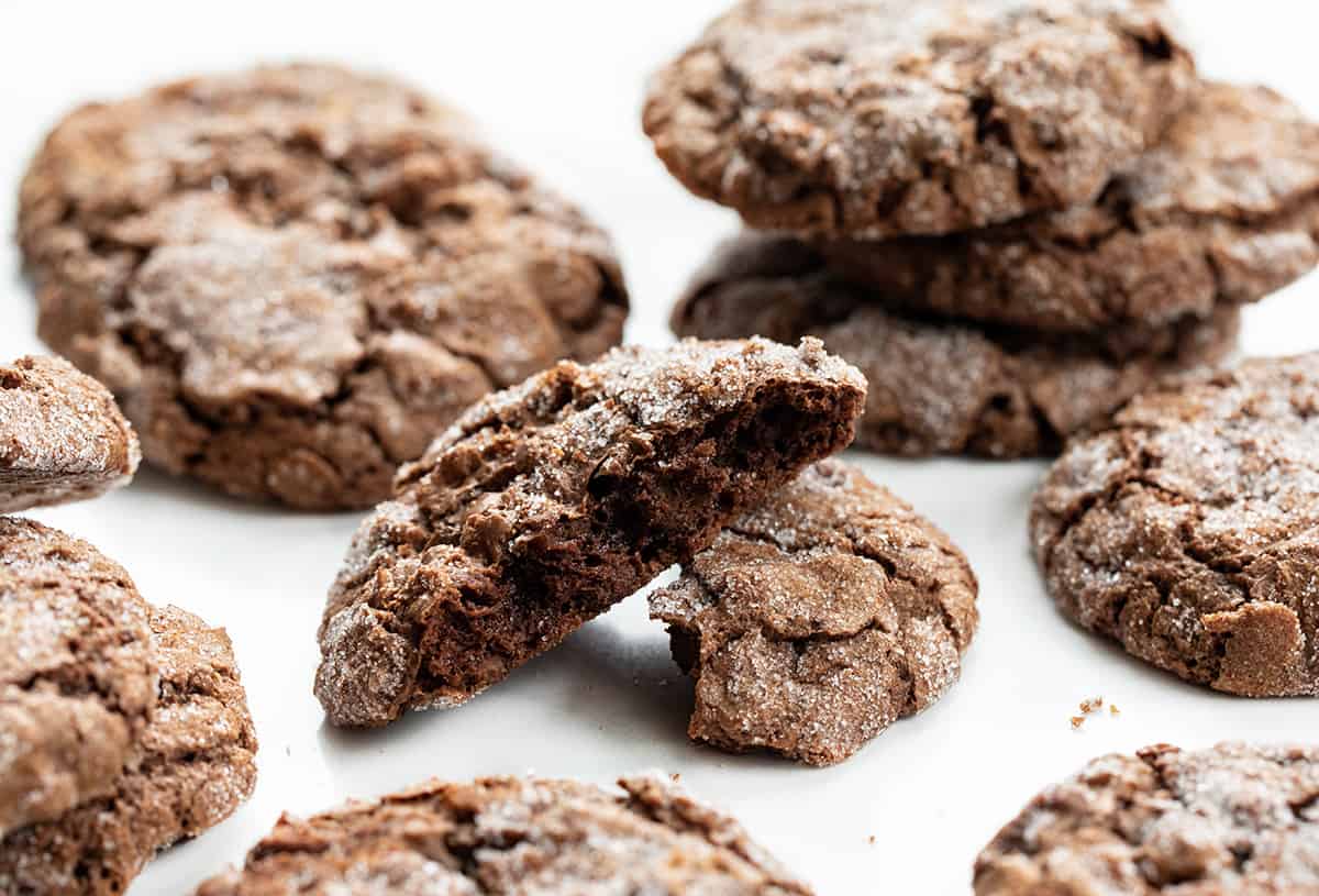 Dirty Chocolate Cookies on a White Counter with One Cookies Broken Showing the Inside Texture.