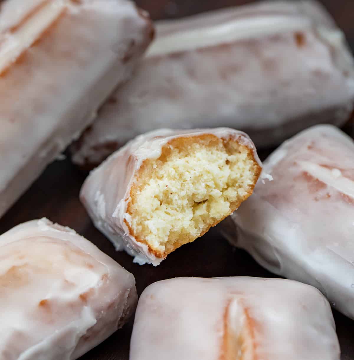 Donut Sticks on a Butcher Block with One Torn in Half Showing Inside.