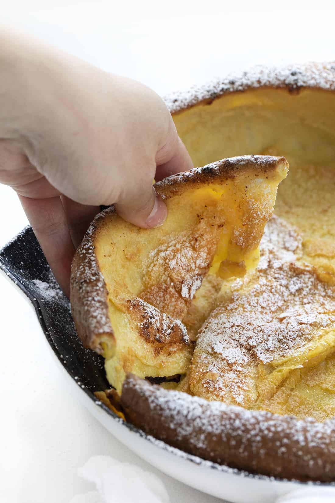 Hand Picking up Dutch Baby Pancake