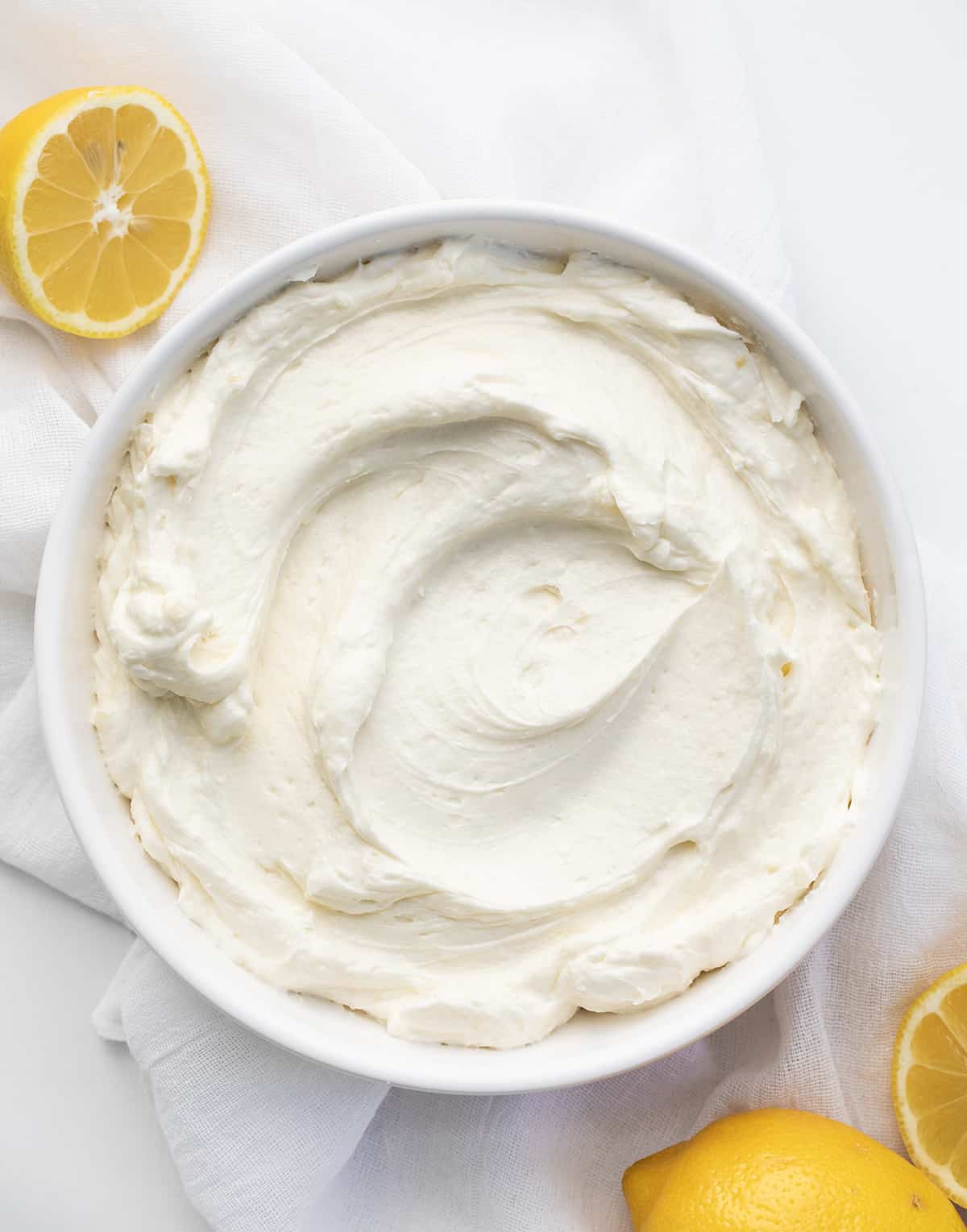 Bowl of Lemon Ermine Frosting Smoothed Out with Lemons around.