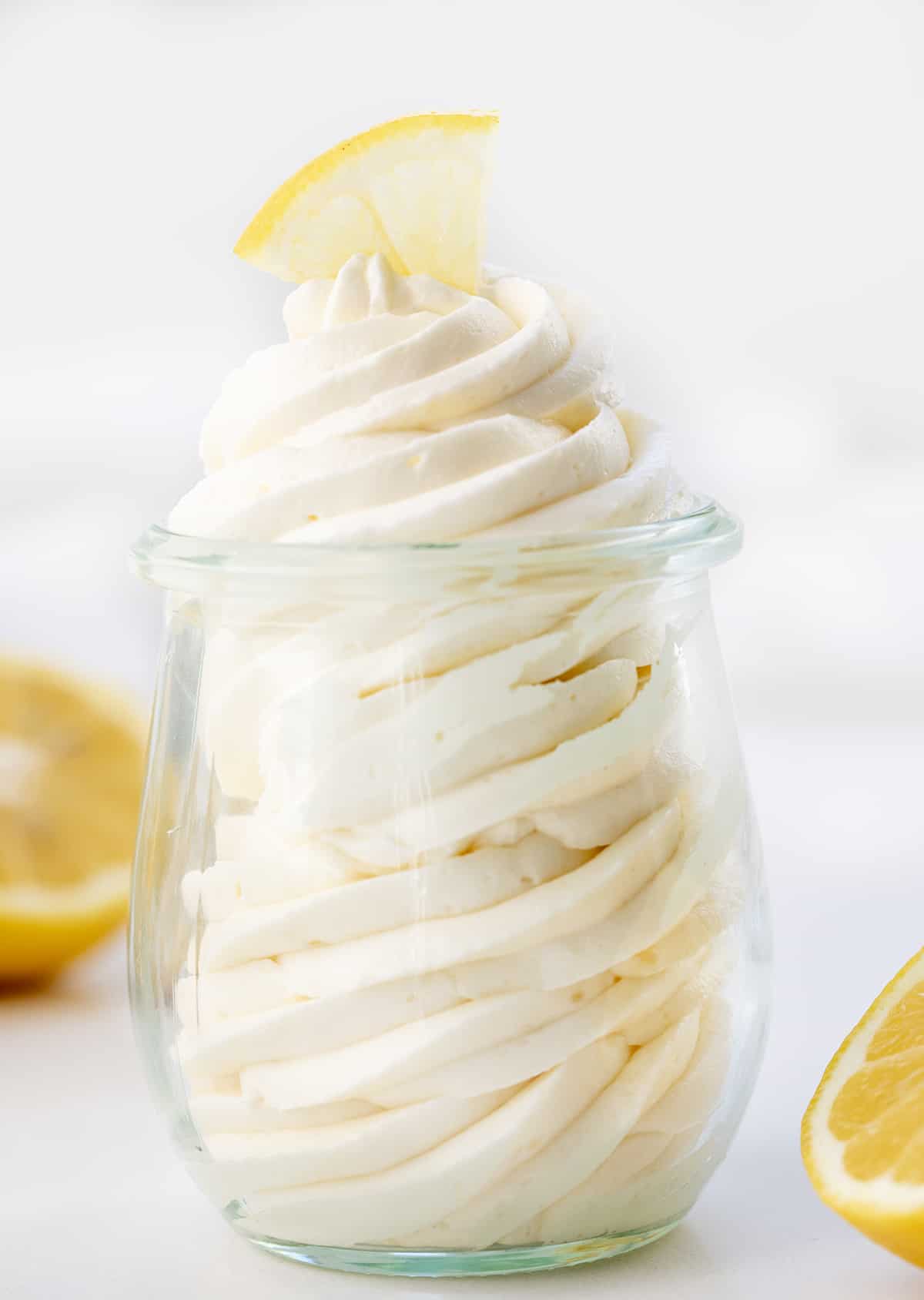 Lemon Ermine Frosting Piped into a Glass Jar with Lemons around it. 