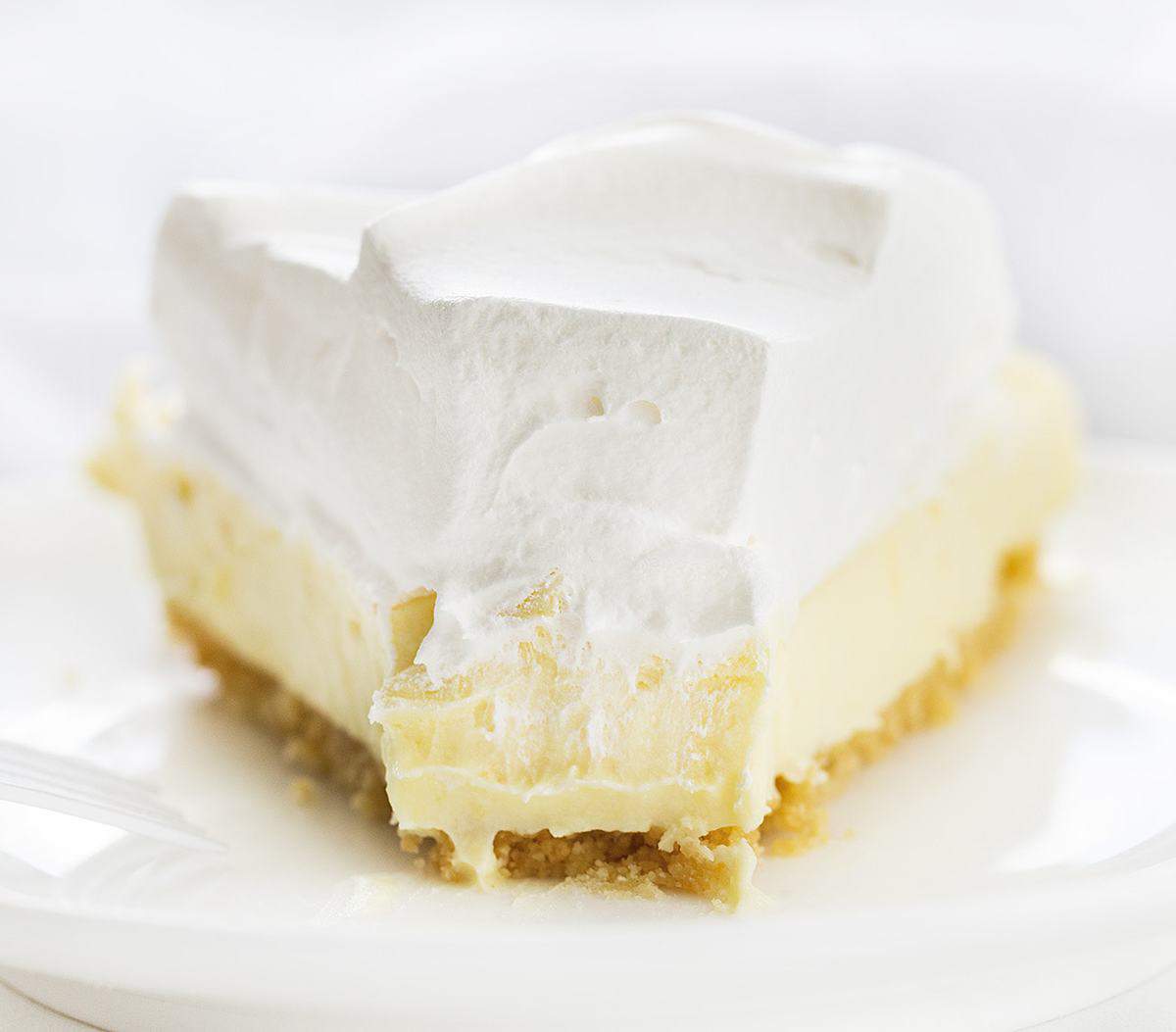 One Piece of Lemonade Pie with a Bite Missing and Fork Resting on Plate