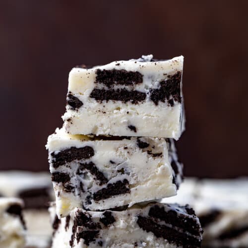 Stack of Cookies and Cream Fudge on a Dark Cutting Board.