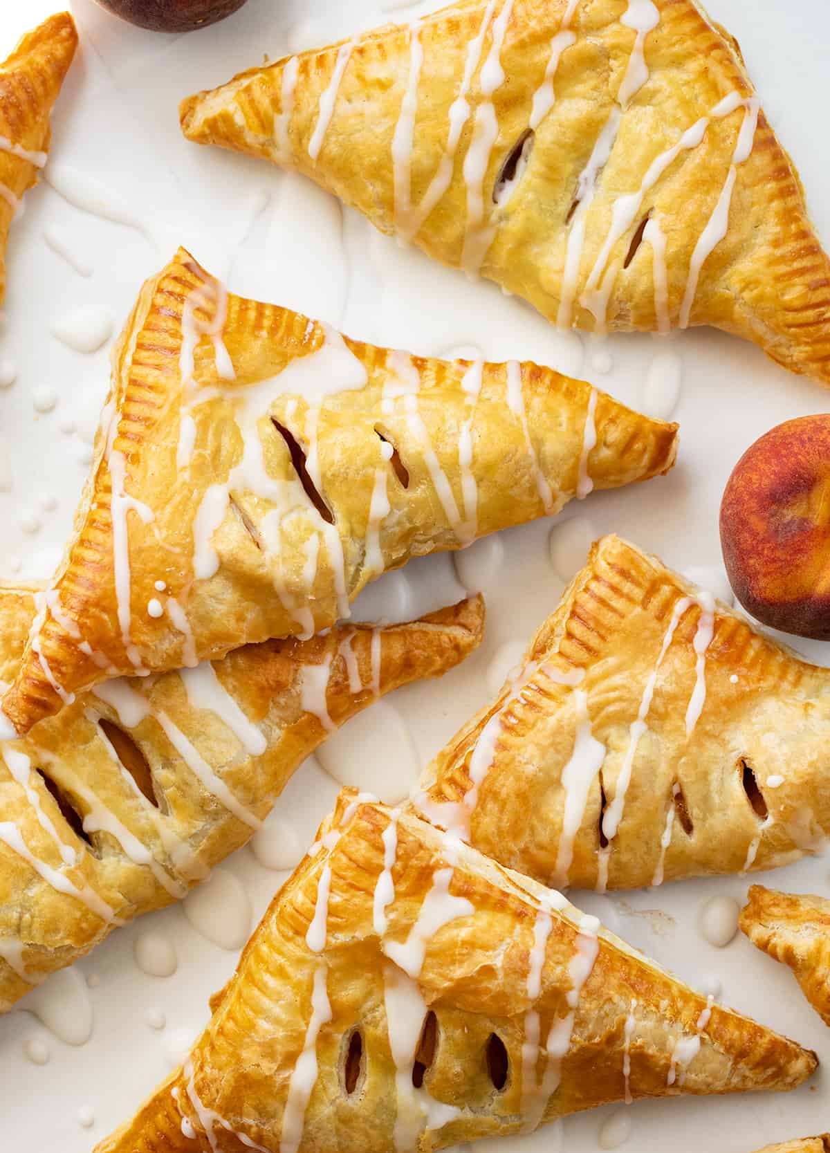 Peach Turnovers on a Piece of White Parchment with Peaches.