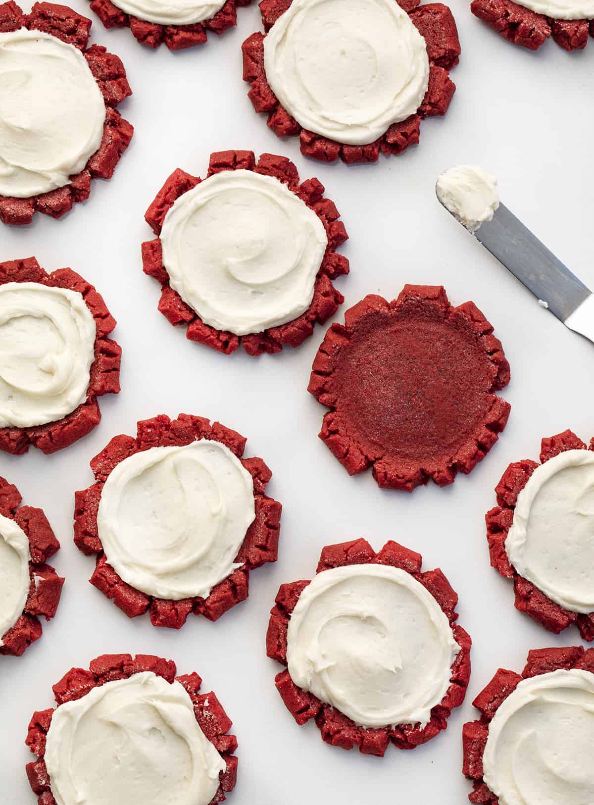 Red Velvet Sugar Cookies with Cream Cheese Frosting With One Cookie Unfrosted next to an Offset Spatula. Dessert, Cookies, Baking, Christmas Cookies, Holiday Baking, Cookie Exchange, Red Velvet Recipes, Red Velvet Cookies, Cream Cheese Frosting, Frosted Sugar Cookies, i am baker, iambaker