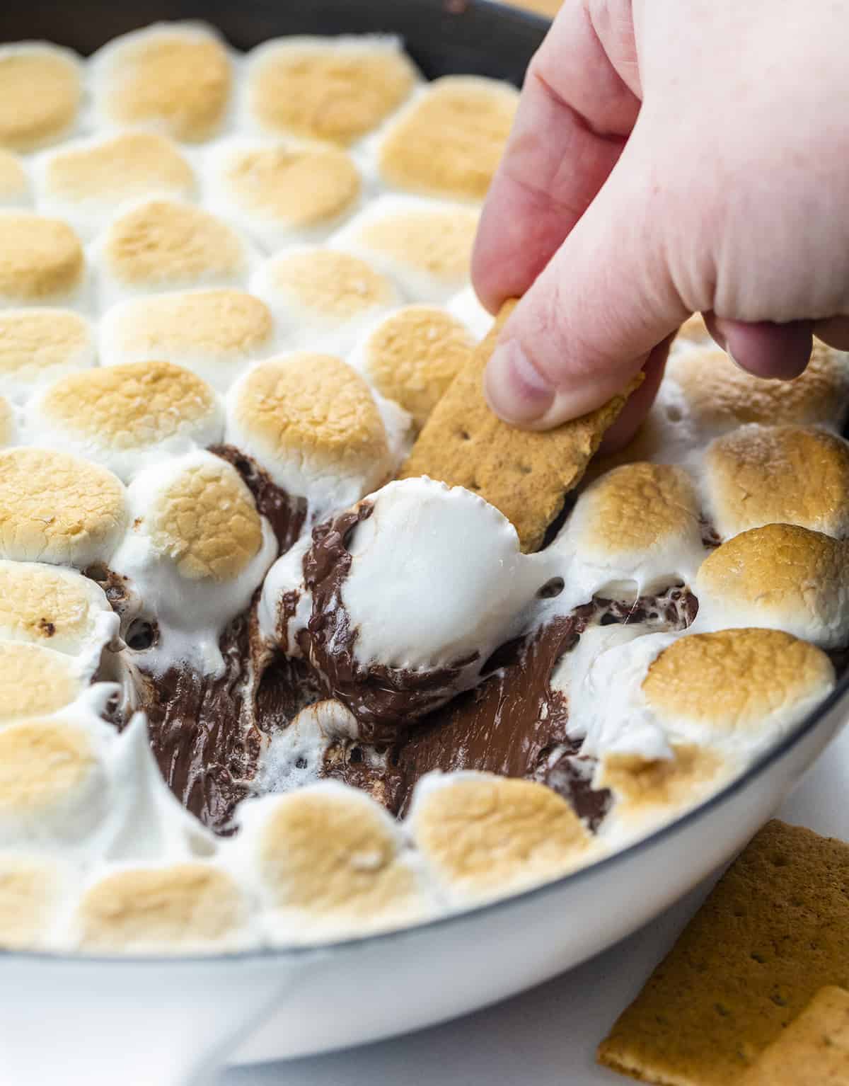 Hand Dipping Graham Cracker into Smores Dip 