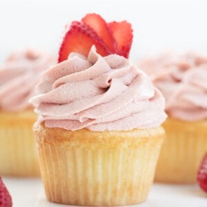 Strawberry Ermine Frosting Piped on a Cupcake with Strawberries.