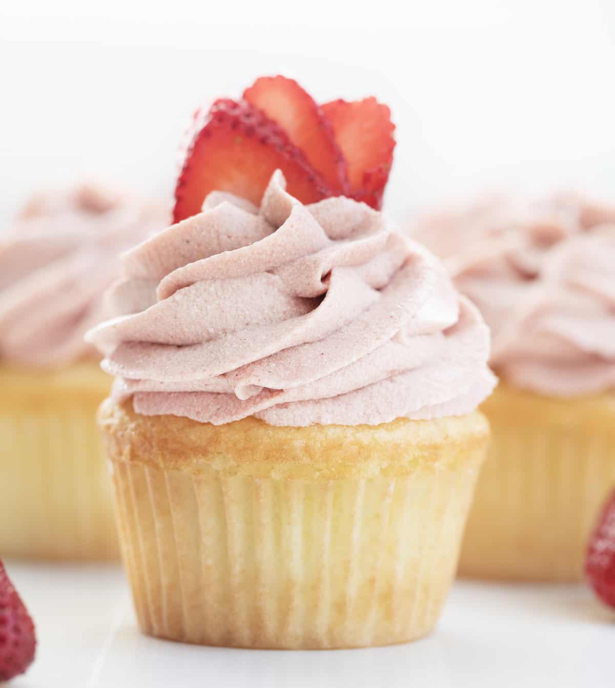 Strawberry Ermine Frosting Piped on a Cupcake with Strawberries.