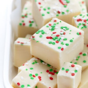 Pieces of Sugar Cookie Fudge that has green and red sprinkles in a dish.