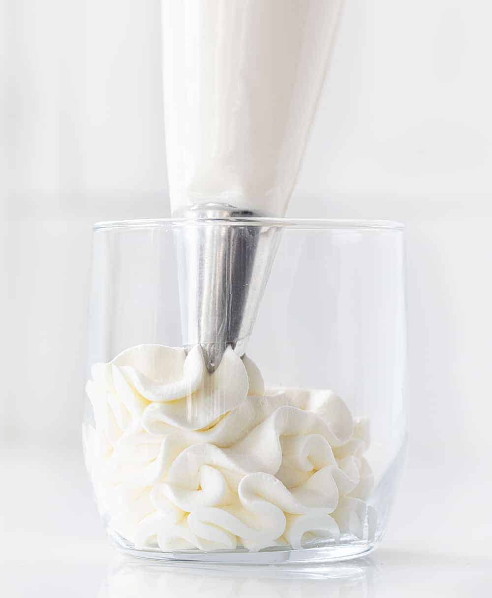 Piping Bag Filled with Homemade Whipped Cream Piping it Into Glass