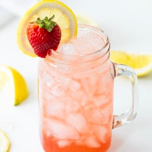 Glass Mug with Whiskey Strawberry Lemonade and a Strawberry and Lemon Garnish.